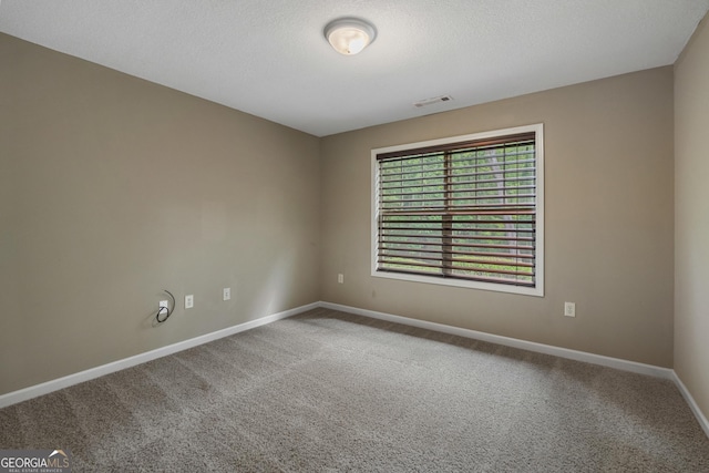 empty room with carpet floors, visible vents, a textured ceiling, and baseboards