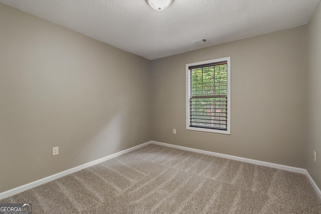 unfurnished room featuring carpet floors, baseboards, visible vents, and a textured ceiling