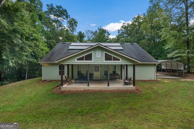 back of property with a carport, roof mounted solar panels, a lawn, and a patio