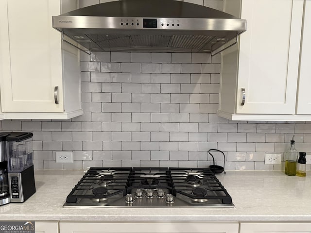 kitchen featuring under cabinet range hood, white cabinetry, light countertops, and stainless steel gas cooktop