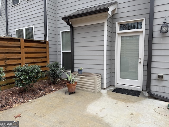 view of exterior entry featuring a patio area and fence