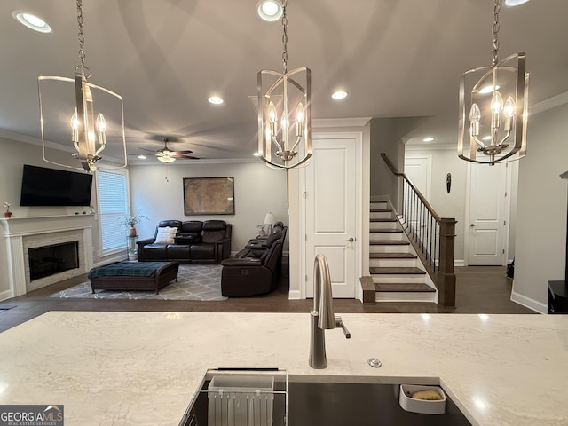 kitchen featuring crown molding, a fireplace, ceiling fan with notable chandelier, and recessed lighting