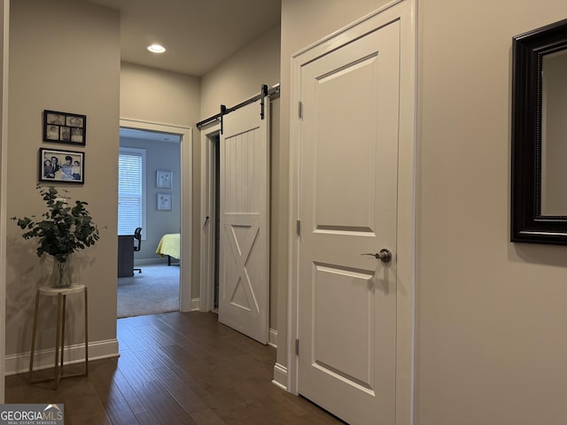 corridor featuring recessed lighting, a barn door, baseboards, and dark wood-style floors