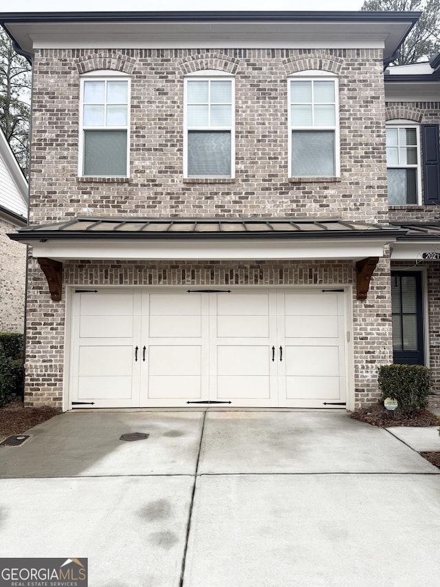 exterior space with an attached garage, brick siding, and driveway