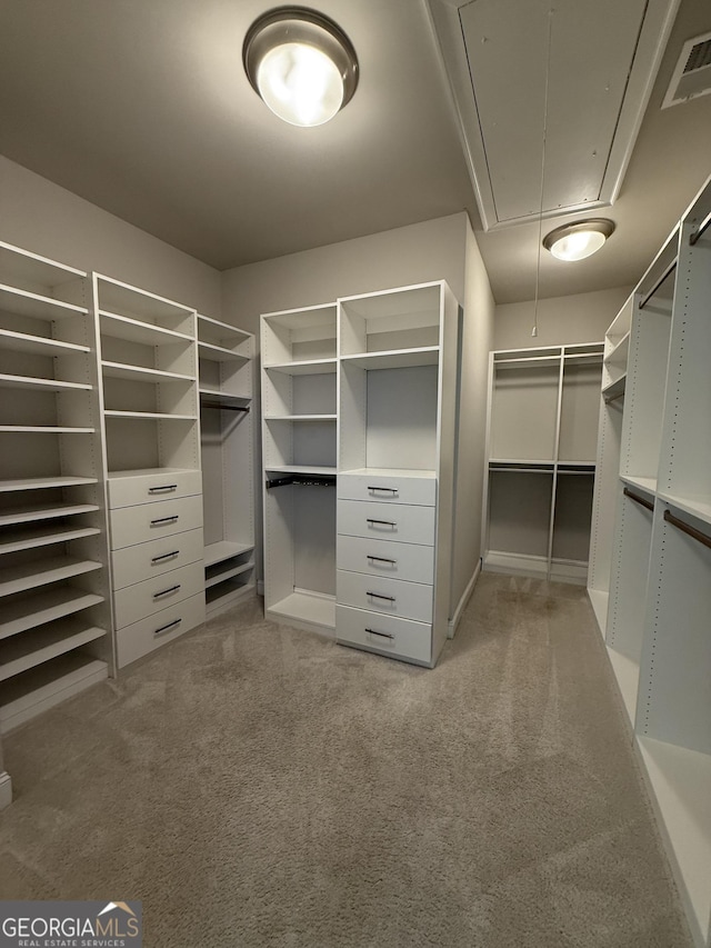 walk in closet featuring light carpet, attic access, and visible vents