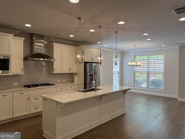 kitchen featuring a sink, wall chimney exhaust hood, visible vents, appliances with stainless steel finishes, and ornamental molding