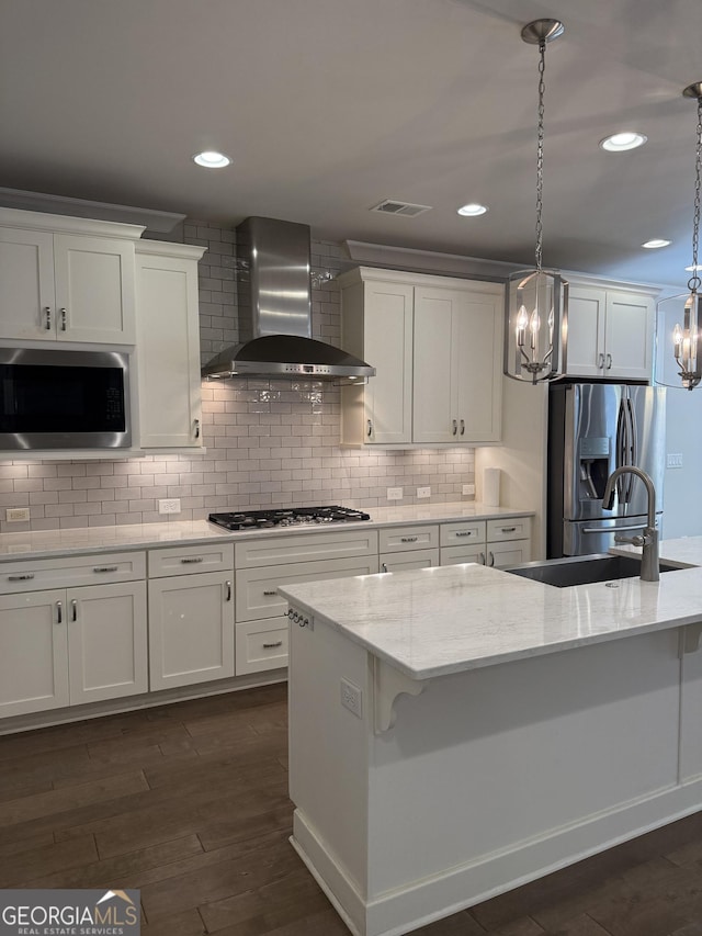 kitchen featuring visible vents, a sink, a chandelier, wall chimney range hood, and appliances with stainless steel finishes