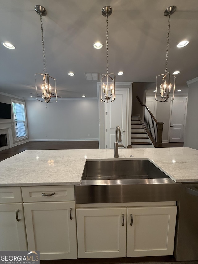 kitchen featuring white cabinetry, a chandelier, light stone countertops, and a sink