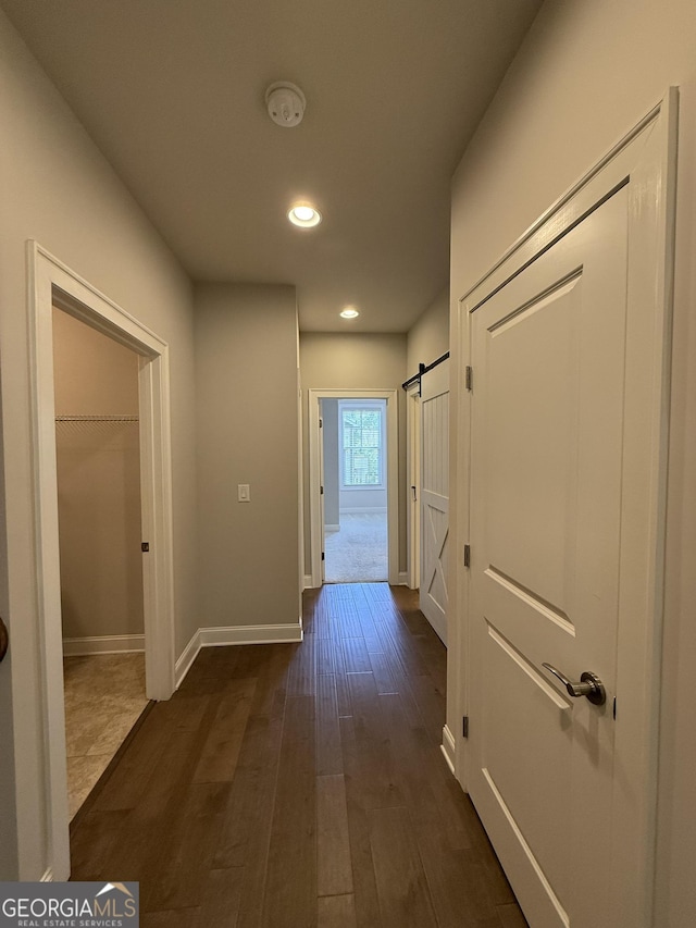 corridor with baseboards, recessed lighting, and dark wood-type flooring