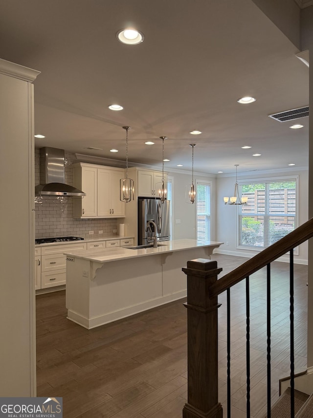 kitchen featuring a notable chandelier, recessed lighting, gas cooktop, a kitchen breakfast bar, and wall chimney range hood