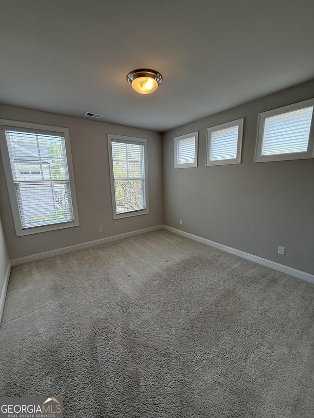 carpeted empty room featuring baseboards and visible vents