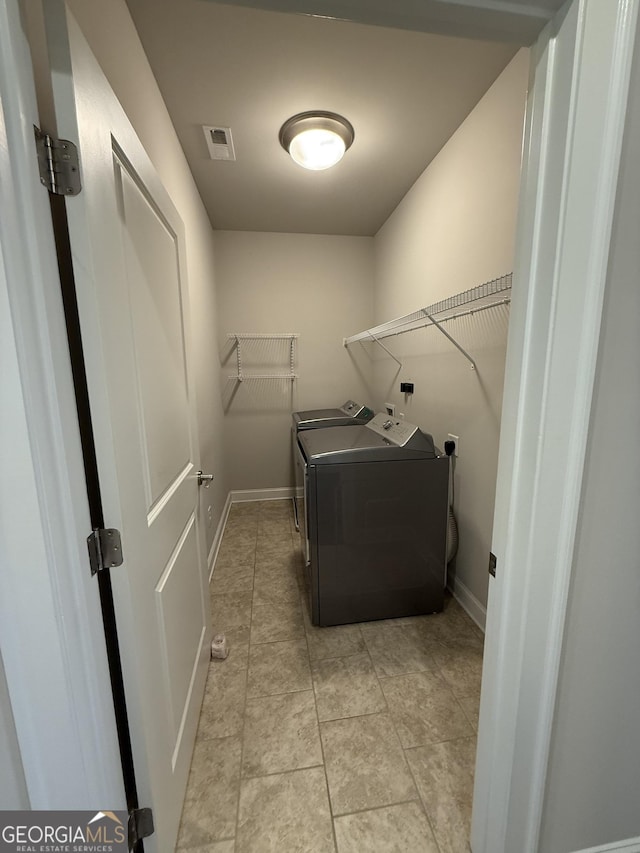 washroom with washing machine and clothes dryer, laundry area, baseboards, and visible vents