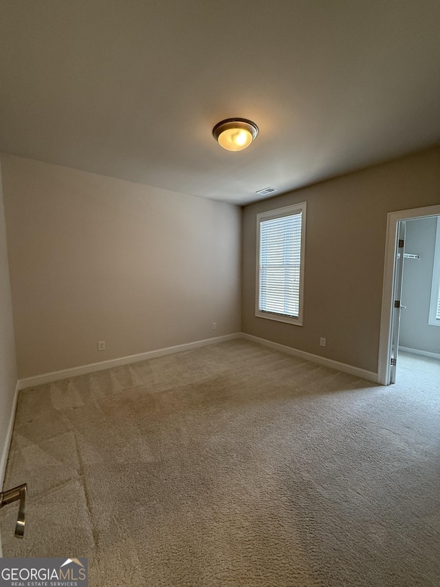 empty room featuring carpet and baseboards