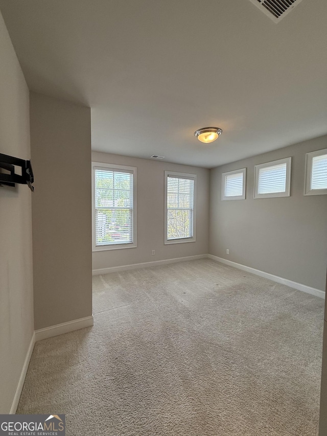unfurnished room featuring light colored carpet, baseboards, and visible vents