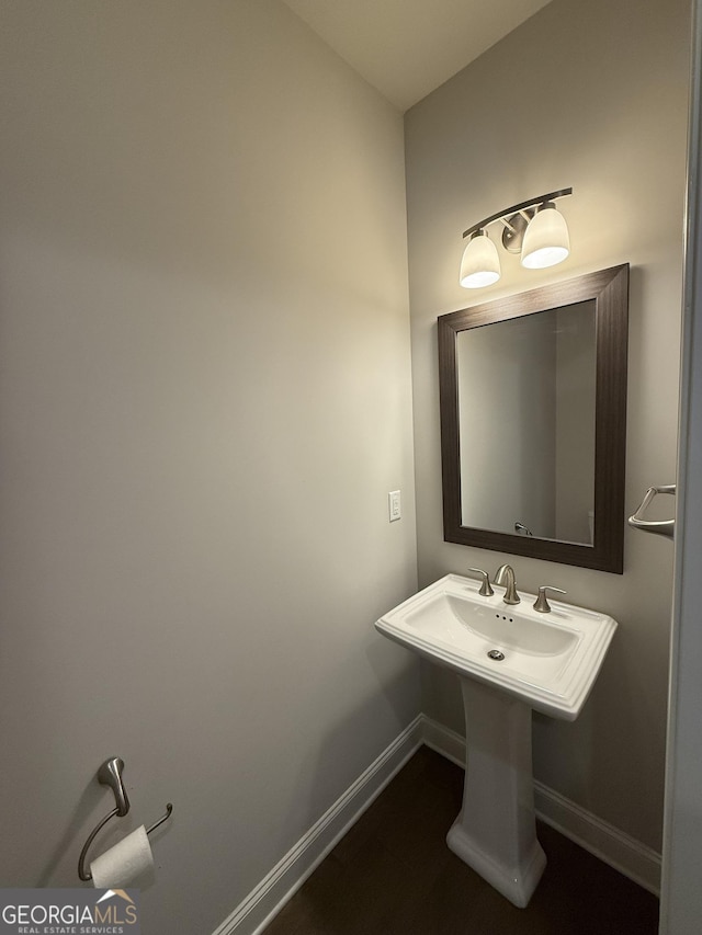 bathroom featuring baseboards, a sink, and wood finished floors