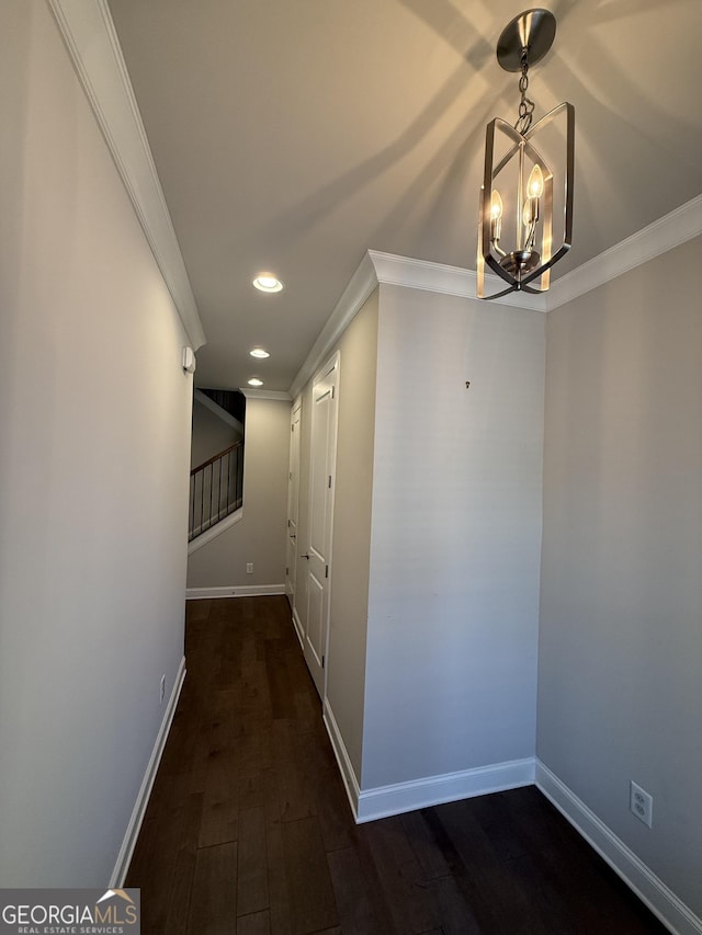 hallway with a notable chandelier, crown molding, dark wood-style flooring, baseboards, and recessed lighting