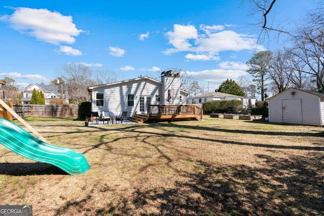 rear view of house with a storage shed, a chimney, fence, an outdoor structure, and a playground