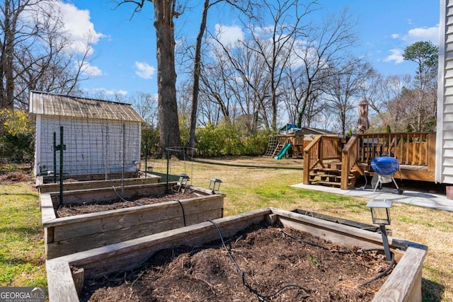 view of yard featuring a playground, a vegetable garden, an outdoor structure, and a shed