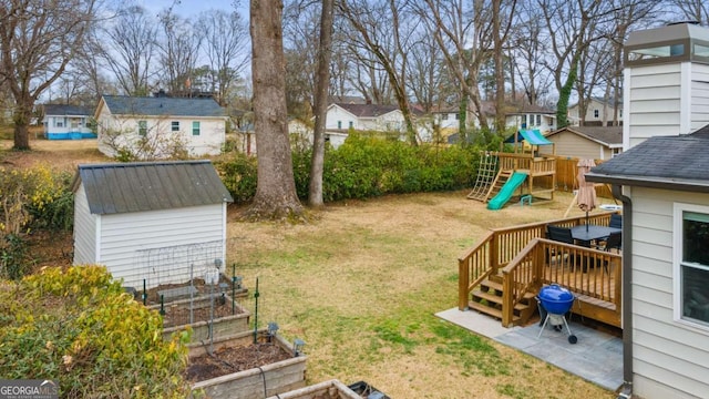 view of yard with a garden, a playground, an outdoor structure, and a shed