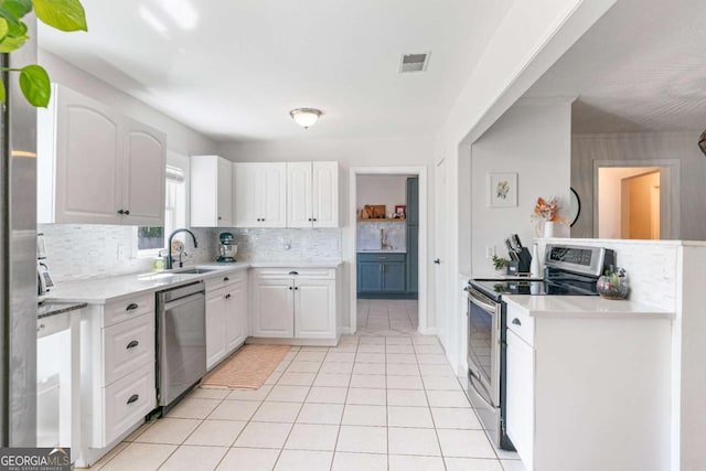 kitchen with light tile patterned floors, stainless steel appliances, a sink, white cabinets, and decorative backsplash