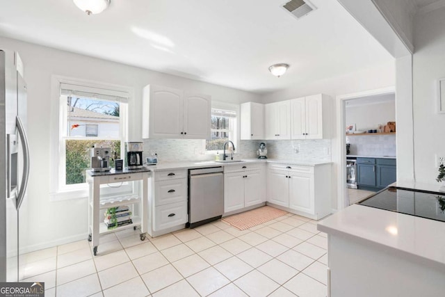 kitchen featuring tasteful backsplash, visible vents, appliances with stainless steel finishes, white cabinetry, and a sink