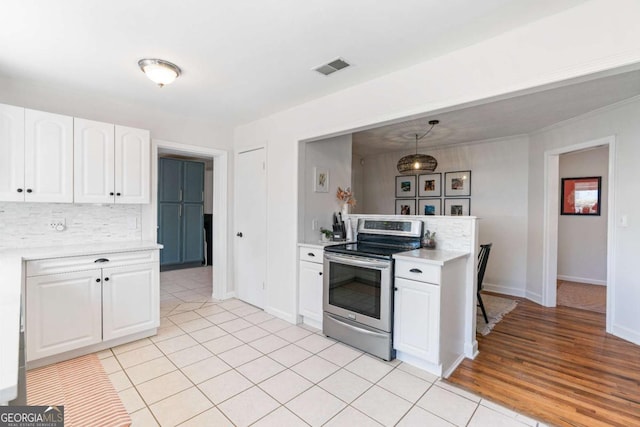 kitchen with visible vents, white cabinets, light countertops, stainless steel electric range oven, and tasteful backsplash