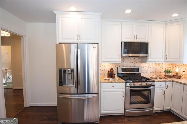 kitchen featuring appliances with stainless steel finishes, light stone countertops, white cabinets, and tasteful backsplash