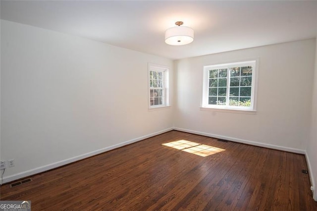 spare room with visible vents, baseboards, and wood finished floors