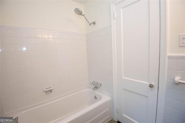 full bath with wainscoting, shower / bathing tub combination, and tile walls