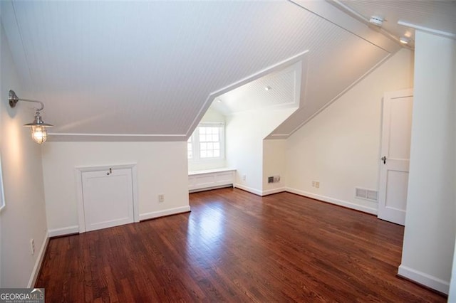 additional living space with baseboards, visible vents, vaulted ceiling, and wood finished floors