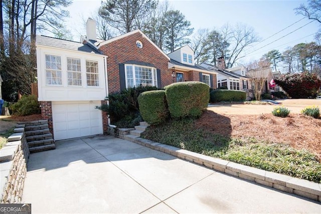 view of front of home featuring an attached garage, a chimney, concrete driveway, and brick siding