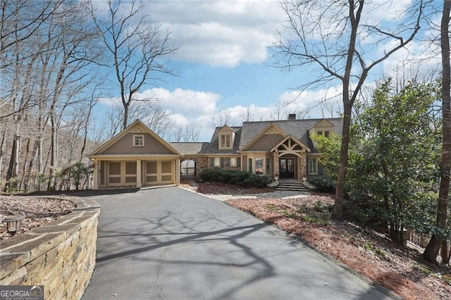 view of front of property featuring aphalt driveway, a chimney, and a garage