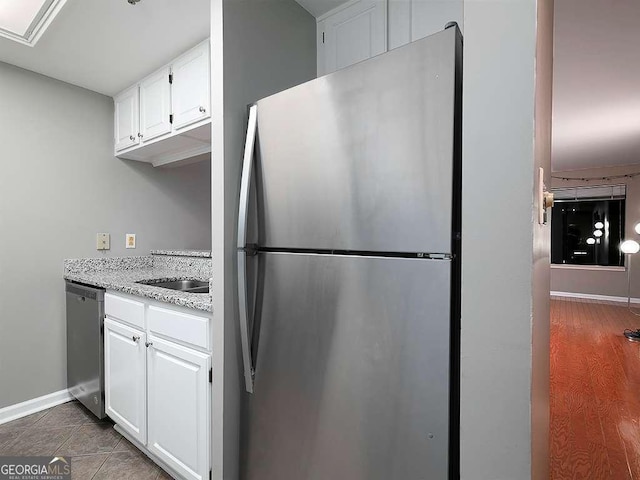 kitchen featuring light stone counters, tile patterned flooring, stainless steel appliances, baseboards, and white cabinets