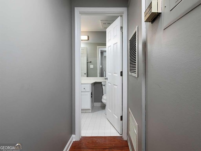 hallway with baseboards, visible vents, and tile patterned floors