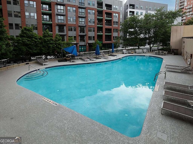 pool with a patio area and fence