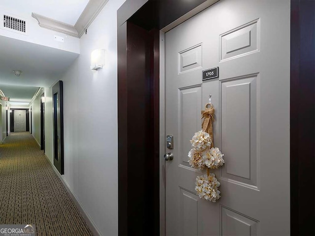 hallway with visible vents, carpet flooring, and ornamental molding