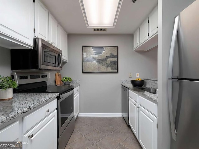 kitchen featuring stainless steel appliances, visible vents, white cabinetry, light tile patterned flooring, and baseboards