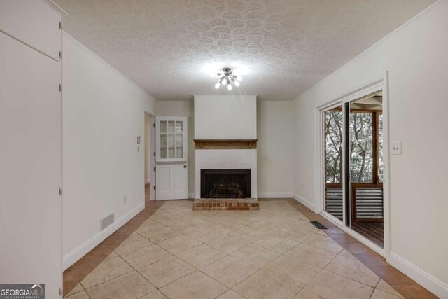 unfurnished living room with a textured ceiling, light tile patterned flooring, a fireplace, visible vents, and ornamental molding