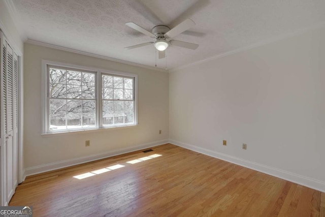 unfurnished bedroom with a closet, visible vents, crown molding, and light wood finished floors