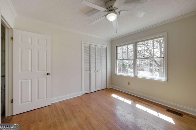 unfurnished bedroom with ornamental molding, light wood-type flooring, visible vents, and baseboards