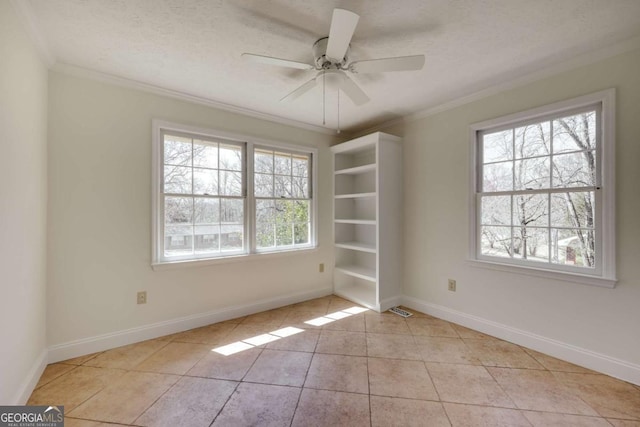 empty room with a ceiling fan, tile patterned flooring, ornamental molding, and baseboards