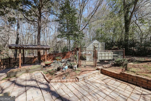 view of patio / terrace featuring a greenhouse, an outdoor structure, and fence