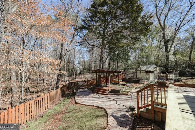 view of yard with fence, a deck, an exterior structure, and an outbuilding