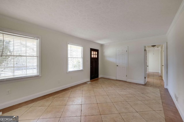 foyer with light tile patterned floors, baseboards, a textured ceiling, and ornamental molding