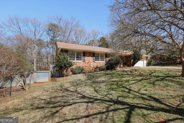 view of front of home featuring an attached garage, a gate, fence, a front yard, and brick siding