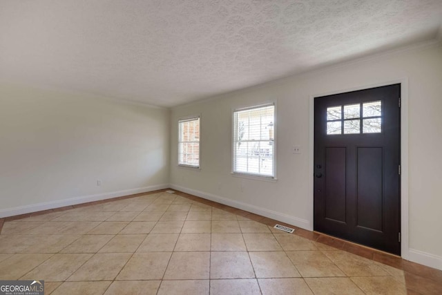 entrance foyer with a textured ceiling, light tile patterned flooring, visible vents, and baseboards