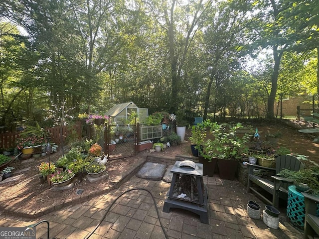 view of patio / terrace featuring a vegetable garden, an exterior structure, an outdoor fire pit, fence, and an outdoor structure