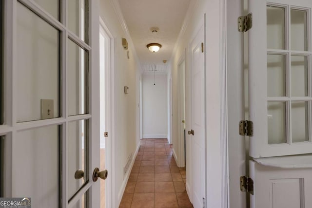 hallway with light tile patterned floors, attic access, and baseboards