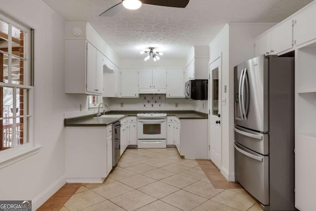 kitchen featuring dark countertops, appliances with stainless steel finishes, crown molding, a textured ceiling, and a sink