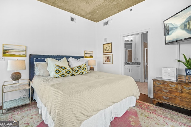 bedroom featuring visible vents, wood finished floors, and ensuite bathroom